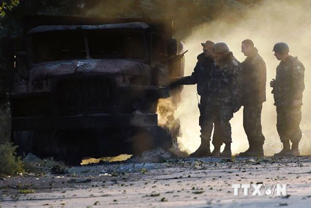 Quân đội Ukraine bên một chiếc xe quân sự bốc cháy sau vụ đánh bom tại một trạm kiểm soát ở ngoại ô thành phố cảng miền Đông Nam Mariupol ngày 7/9.